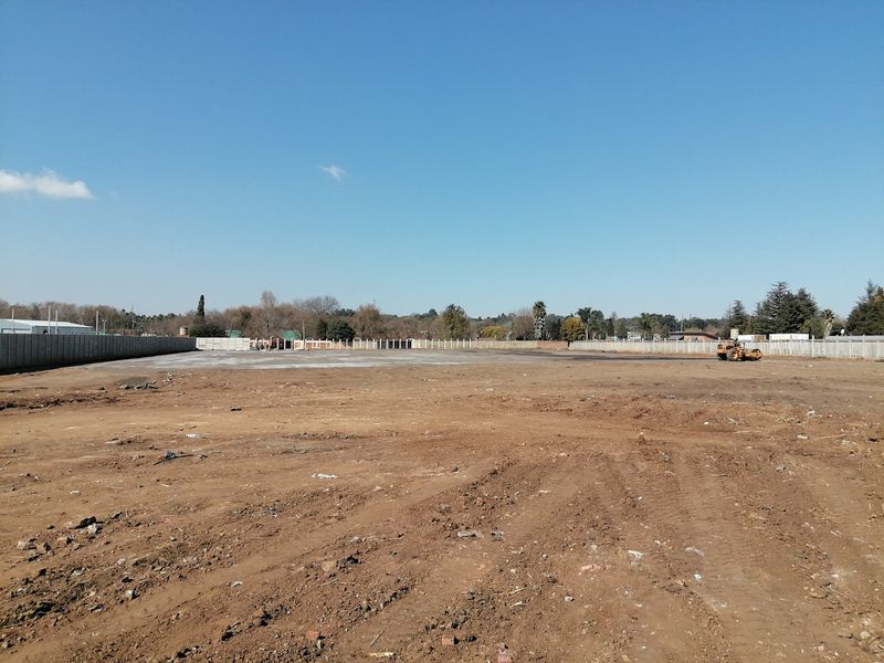 A large, cleared residential vacant land plot enclosed by perimeter concrete walls, ready for development.