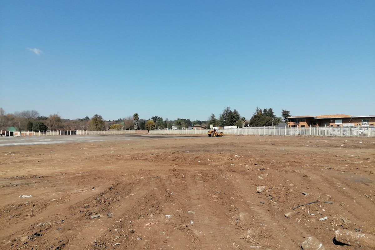 A wide-angle view of a large, cleared residential vacant land plot featuring perimeter fencing and level ground, ready for development.