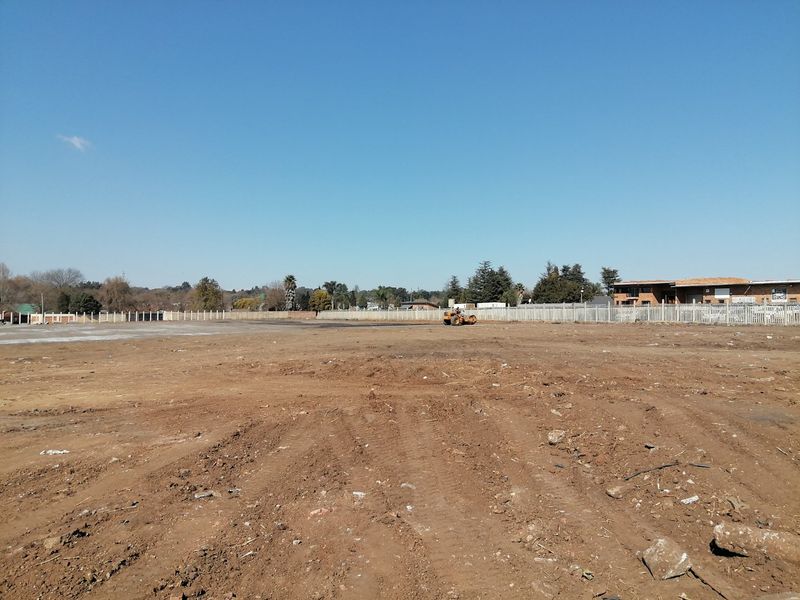 A wide-angle view of a large, cleared residential vacant land plot featuring perimeter fencing and level ground, ready for development.