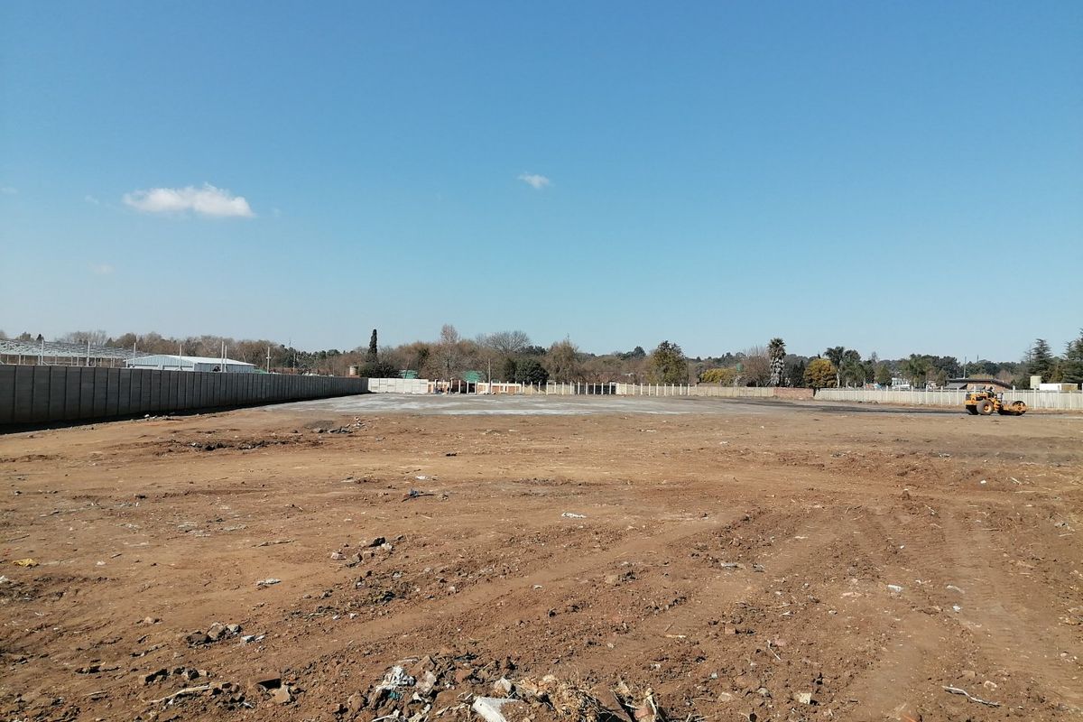 A wide-angle view of a cleared, level residential plot enclosed by a precast concrete boundary wall, ready for development.
