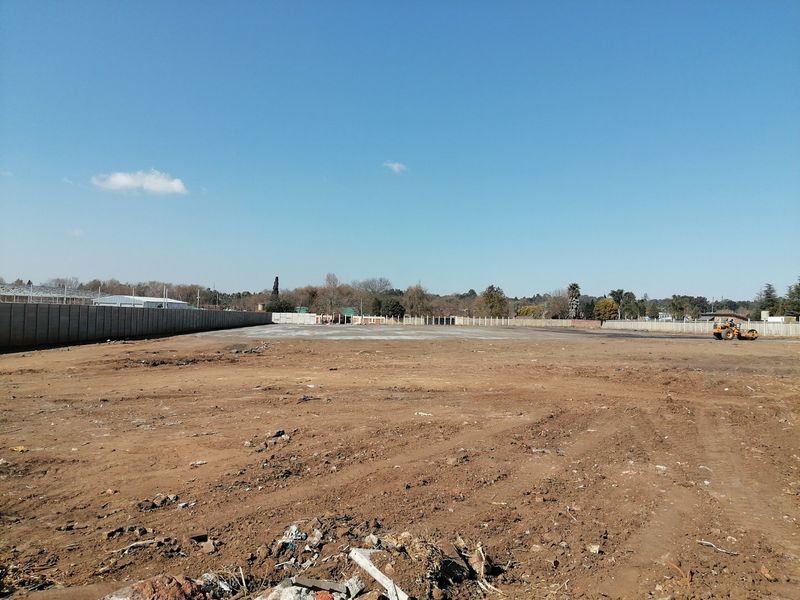 A wide-angle view of a cleared, level residential plot enclosed by a precast concrete boundary wall, ready for development.