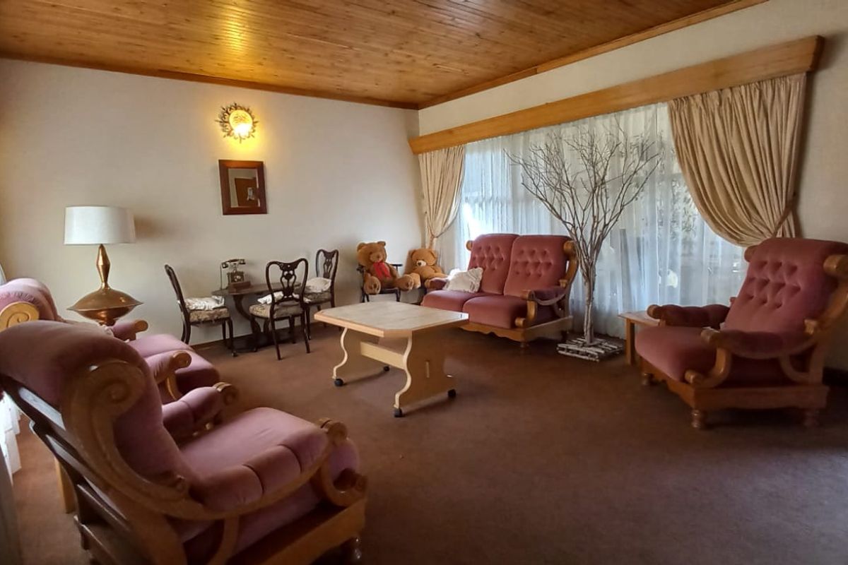 A spacious living room featuring a warm timber ceiling and classic window pelmets, offering a comfortable and traditional living space.