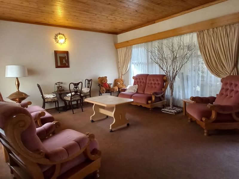 A spacious living room featuring a warm timber ceiling and classic window pelmets, offering a comfortable and traditional living space.