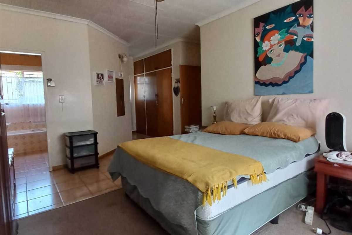 A spacious bedroom featuring built-in cupboards and direct access to an en-suite bathroom, offering a functional layout with neutral finishes.
