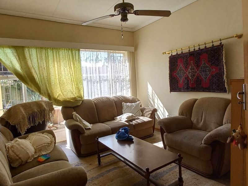 A living room featuring a ceiling fan, large window for natural light, and a built-in cupboard, offering a functional space for relaxation.