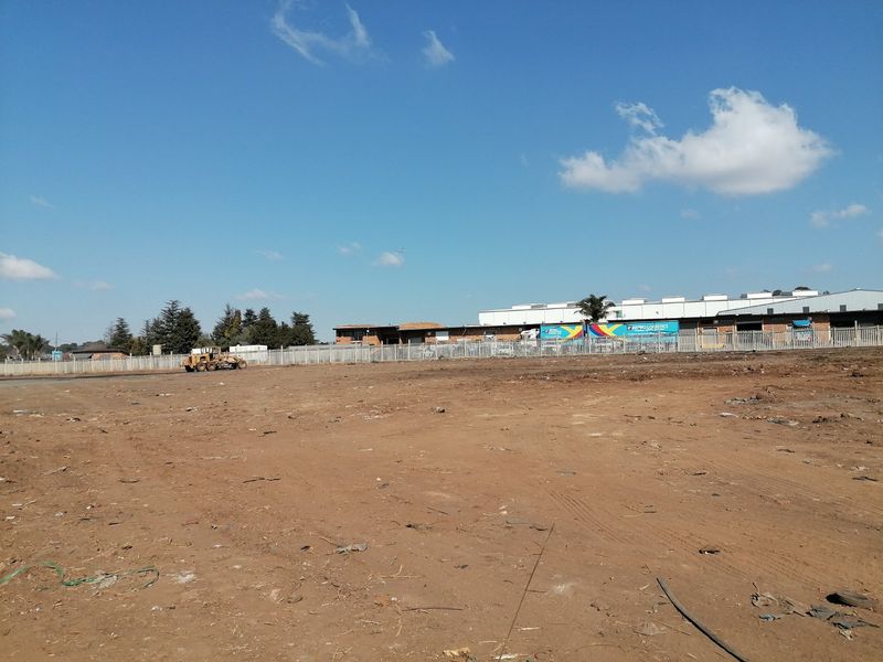 A view of a vacant residential plot of land featuring perimeter fencing and clear ground, ready for development.