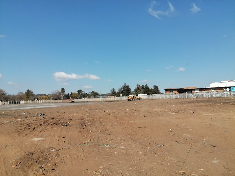 A wide-angle view of a vacant residential plot featuring cleared ground and perimeter fencing, ready for development.