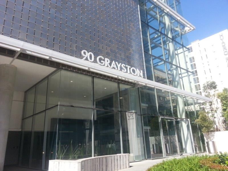 Modern commercial office building facade featuring extensive glass curtain walling, metal mesh cladding, and a prominent entrance at 90 Grayston.