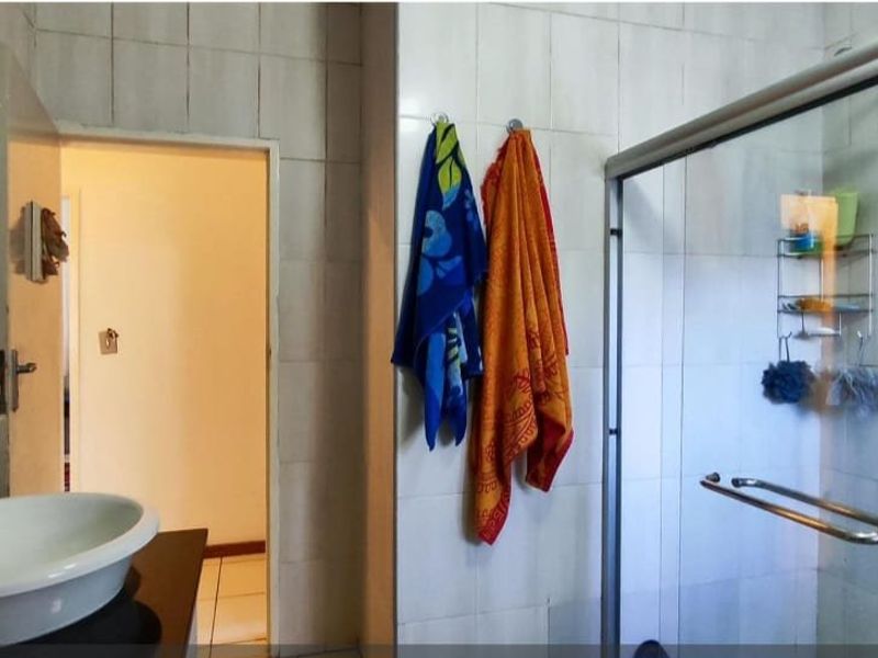 A functional bathroom featuring a vessel sink on a vanity countertop and a glass-enclosed shower with tiled walls.