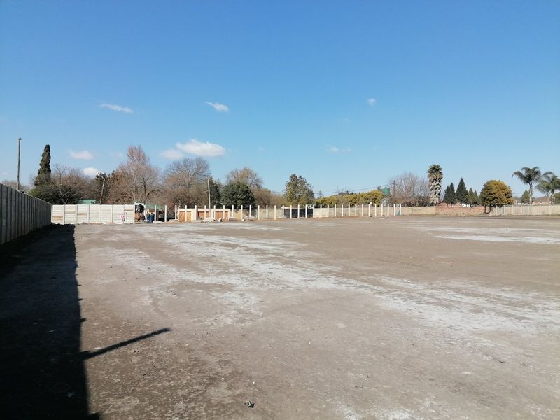 A large, level, and cleared vacant residential plot enclosed by precast concrete boundary walls, ready for development.