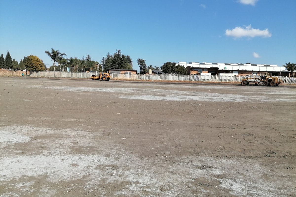 A wide view of a vacant residential plot currently undergoing site preparation and leveling with heavy machinery.