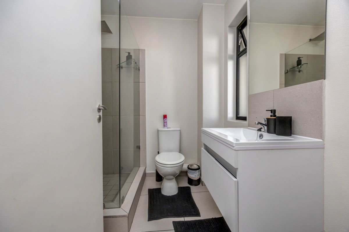 Modern bathroom featuring a glass-enclosed shower, a sleek vanity cabinet with a basin, and a wall-mounted mirror.