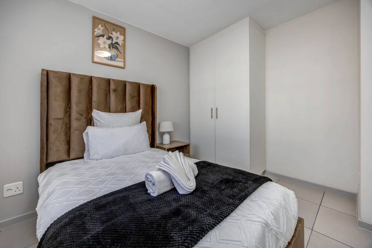 A well-maintained bedroom featuring neutral wall tones, tiled flooring, and a functional built-in wardrobe for storage.