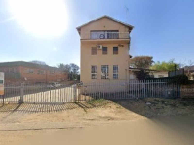 Front view of a multi-story commercial building featuring a gated entrance, perimeter fencing, and an upper-level balcony.