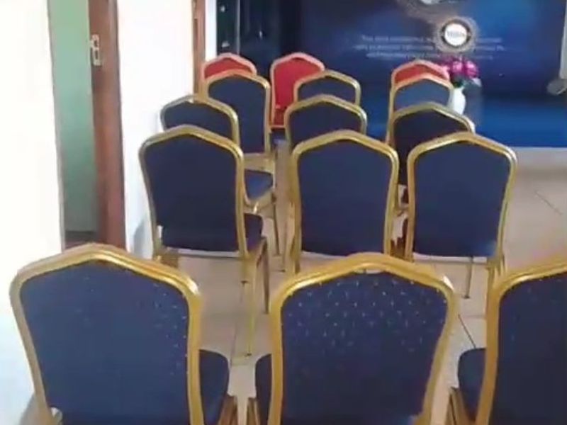 A functional commercial event space featuring tiled flooring and a raised stage area, suitable for meetings or small gatherings.