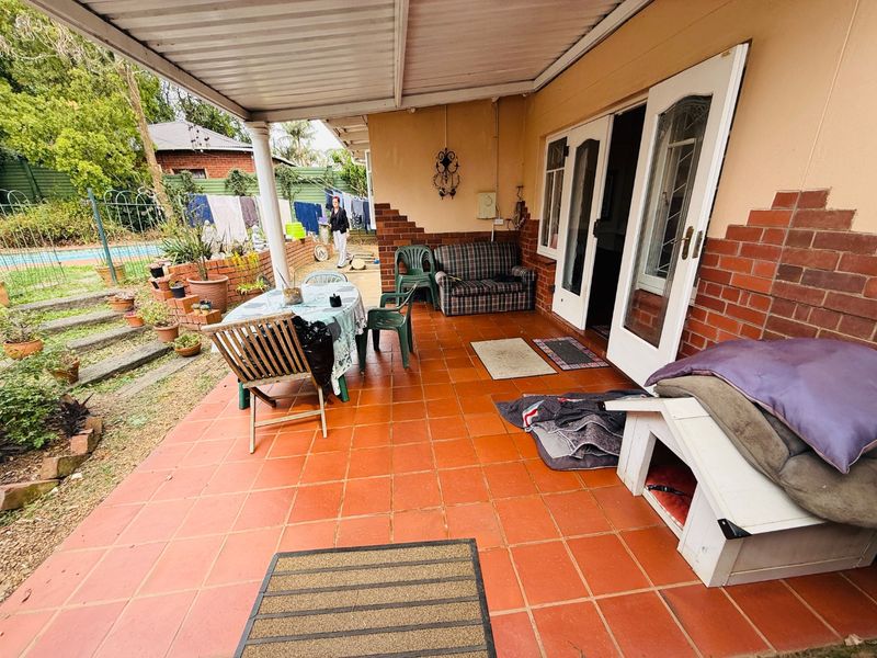 A covered outdoor patio area featuring terracotta tiled flooring and direct access to the home through double glass doors.