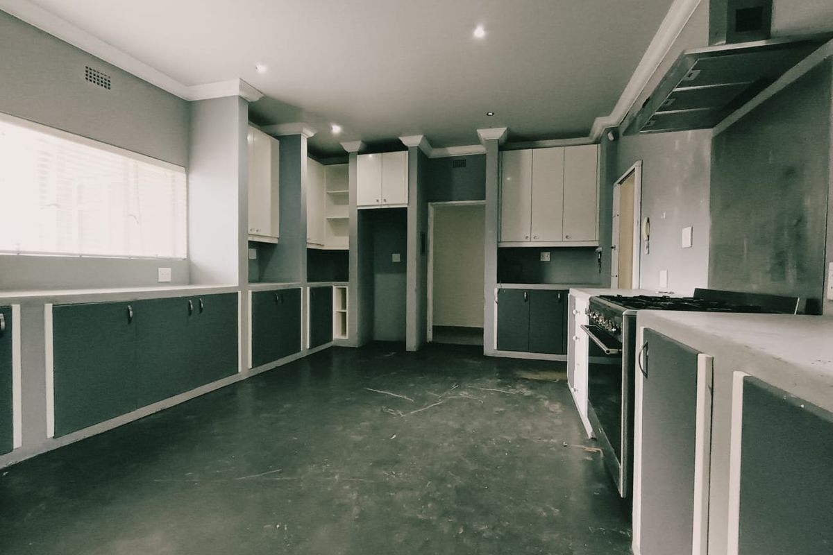 An empty kitchen featuring built-in cabinetry, a freestanding stove with an extractor fan, and recessed lighting, offering a blank canvas for renovation.