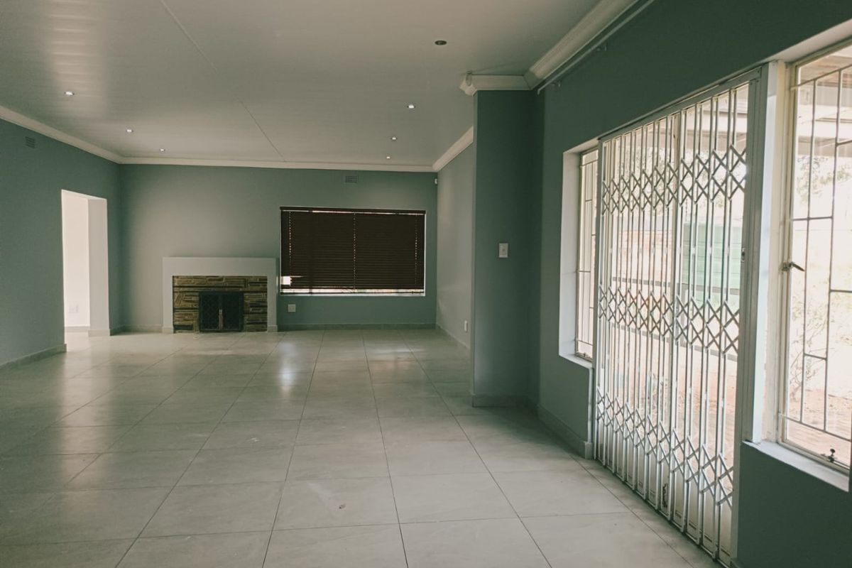 Spacious, light-filled living area featuring neutral tiled flooring, a stone-clad fireplace, and secure sliding door access to the exterior.