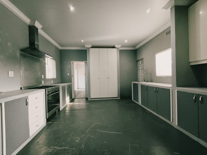 Spacious kitchen featuring built-in cabinetry, a stainless steel extractor fan, a freestanding oven, and a dedicated pantry cupboard.