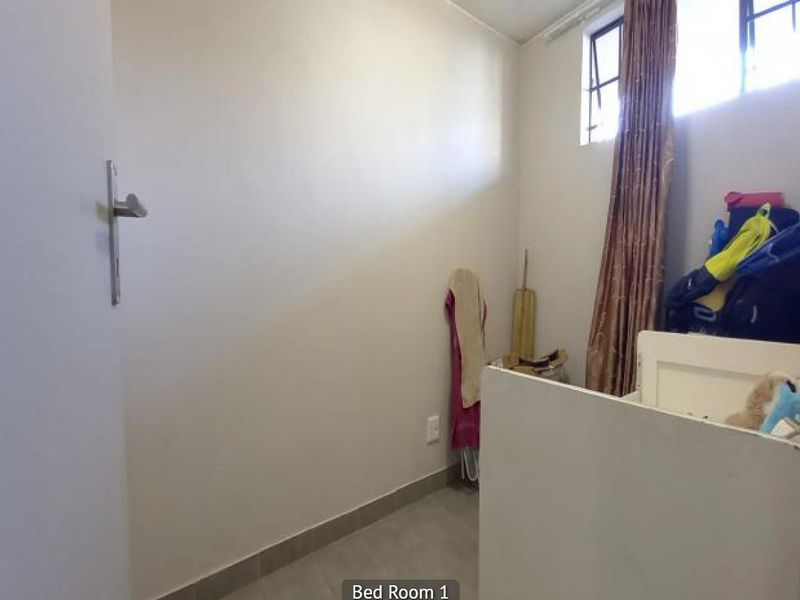 A simple, compact bedroom featuring tiled flooring and a high-level window, providing a functional space ready for personalization.