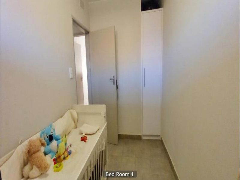 A compact bedroom featuring tiled flooring and a built-in wardrobe, providing functional storage space within the apartment.