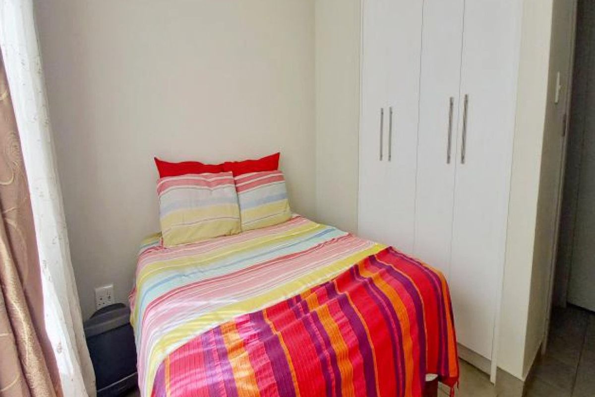 A compact bedroom featuring built-in cupboards and tiled flooring, providing functional storage space.