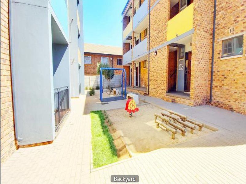 A communal courtyard area featuring a sand pit and playground equipment situated between apartment building blocks.