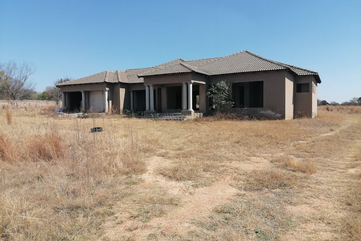 An unfinished single-story residential property featuring a tiled roof and concrete columns, currently in a shell state with no windows or doors installed.