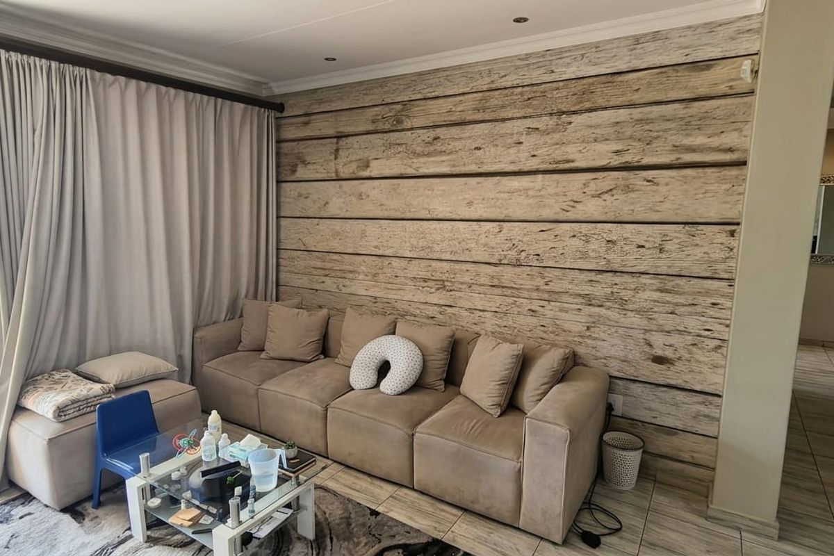 A living room featuring a wood-look accent wall, tiled flooring, and a large sliding glass door providing access to an outdoor balcony.