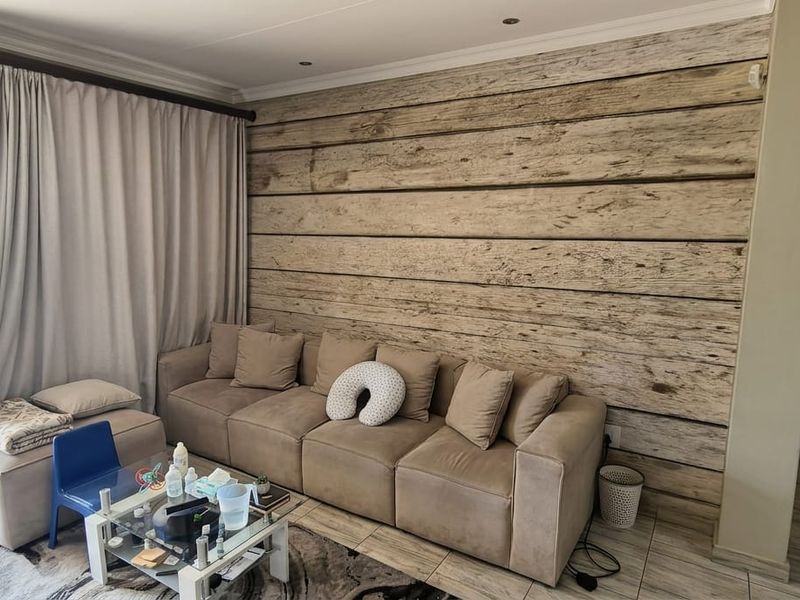A living room featuring a wood-look accent wall, tiled flooring, and a large sliding glass door providing access to an outdoor balcony.