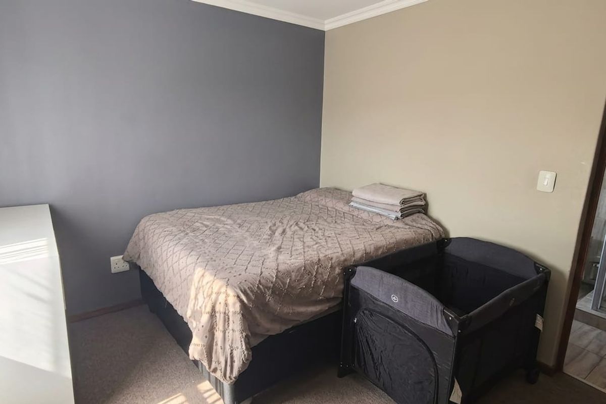 A bedroom featuring an en-suite bathroom with a shower enclosure, neutral wall tones, and carpeted flooring.