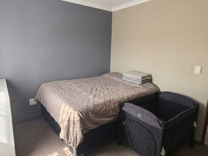 A bedroom featuring an en-suite bathroom with a shower enclosure, neutral wall tones, and carpeted flooring.