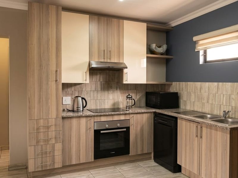 Modern kitchen featuring wood-look cabinetry, granite-style countertops, integrated oven and hob, and a double sink with a tiled backsplash.
