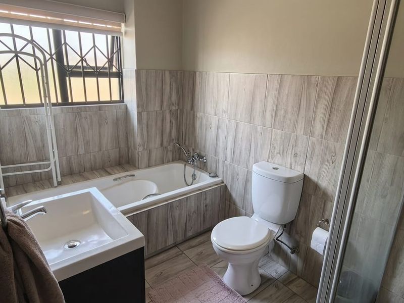 A modern bathroom featuring wood-look tiled walls, a built-in bathtub, a separate shower enclosure, and a vanity basin.