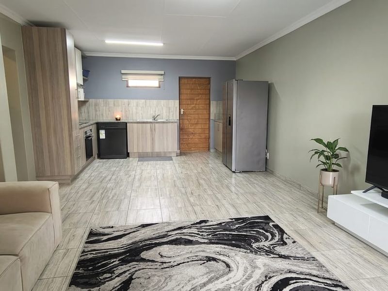 An open-plan living and kitchen area featuring modern wood-look cabinetry, tiled flooring, and a functional layout suitable for contemporary apartment living.