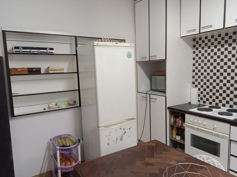 A functional kitchen featuring built-in cabinetry, a checkered tile backsplash, and integrated cooking appliances, offering a practical layout for daily meal preparation.