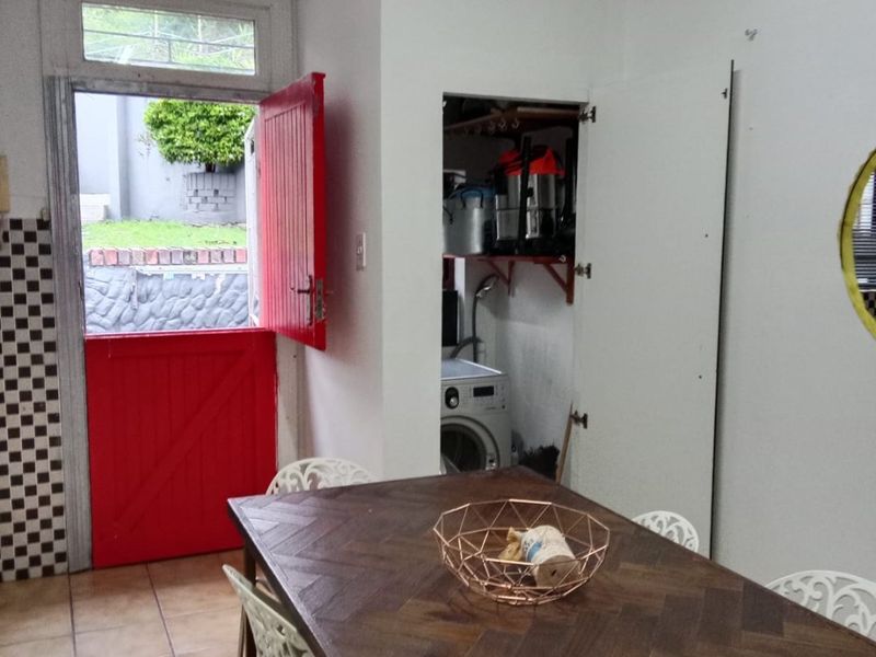 Dining area featuring tiled flooring, a red stable door leading outdoors, and a built-in pantry cupboard with integrated laundry space.