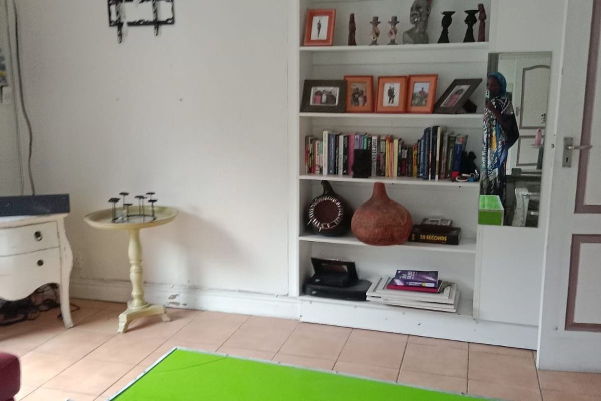 Living room featuring a built-in shelving unit and tiled flooring, offering a functional space with potential for cosmetic updates.