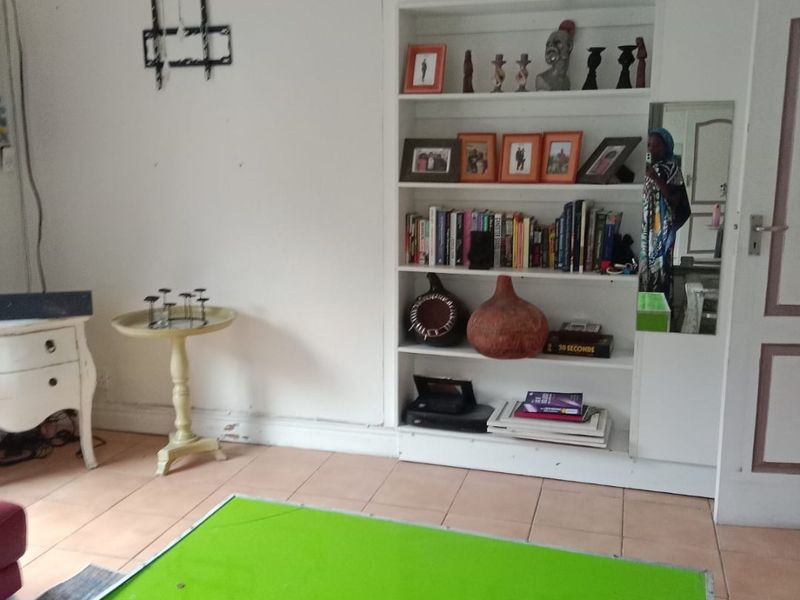 Living room featuring a built-in shelving unit and tiled flooring, offering a functional space with potential for cosmetic updates.