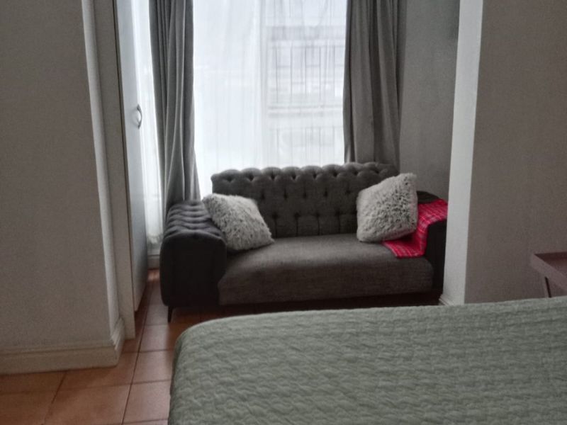A bedroom featuring tiled flooring and a built-in cupboard, with a recessed seating area by the window.
