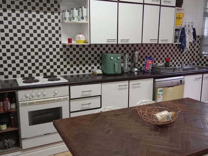 A functional kitchen featuring white cabinetry, a checkerboard tiled backsplash, built-in oven and stove, and tiled flooring.