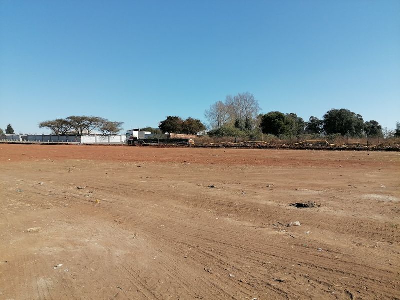 A wide-angle view of a vacant residential plot featuring cleared earth and perimeter fencing, ready for development.