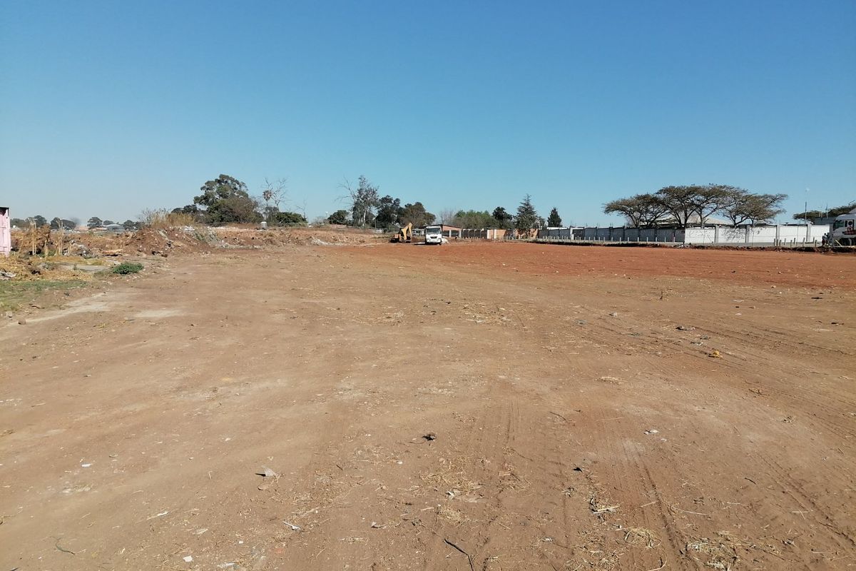 A wide-angle view of a vacant residential plot of land, featuring cleared ground and perimeter boundary walls.