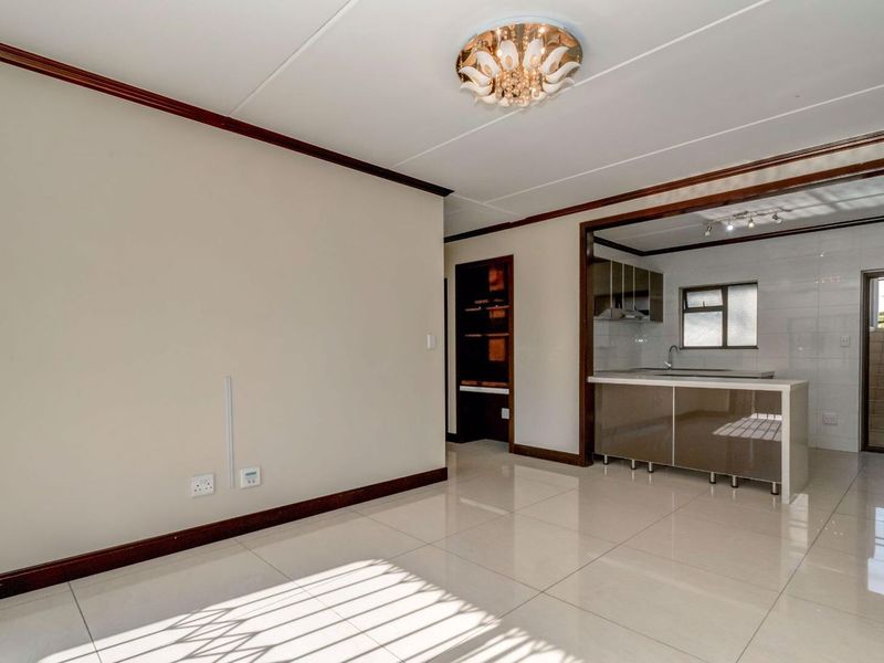 An open-plan living and kitchen area featuring neutral tiled flooring, modern cabinetry, and a bright, spacious layout suitable for versatile furniture arrangements.