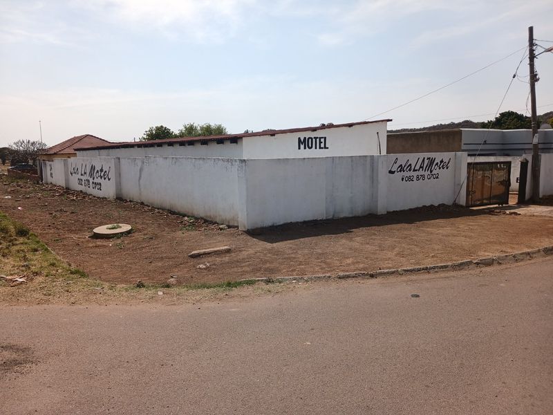 Exterior view of a commercial motel property featuring a perimeter boundary wall, signage, and gated entrance from the street.