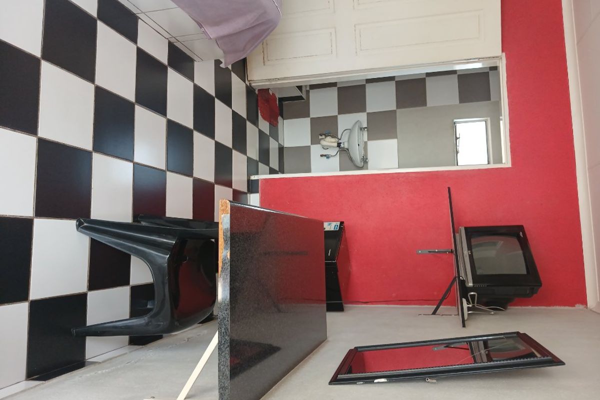 A small bathroom space featuring checkered wall tiling and a wall-mounted basin, currently in need of renovation and repair.