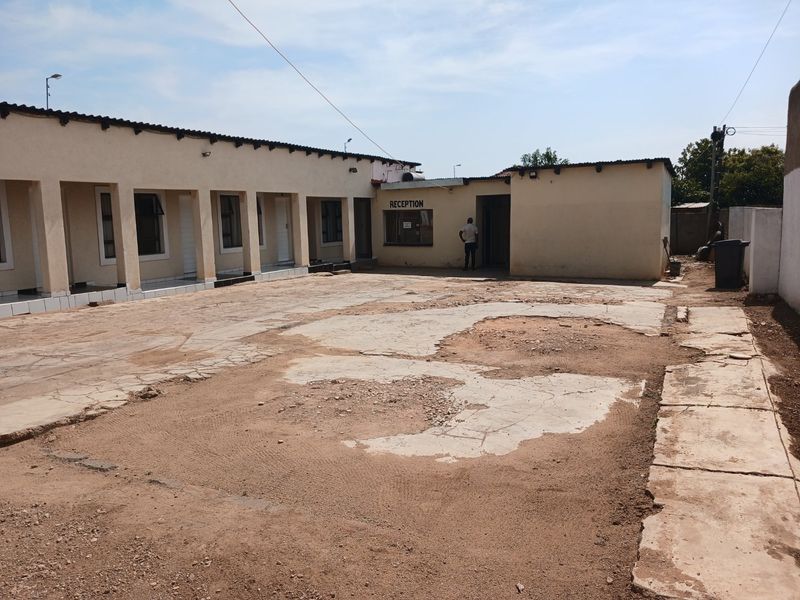 Commercial property courtyard area featuring a reception entrance and covered veranda, currently requiring significant surface repairs and maintenance to the paving.