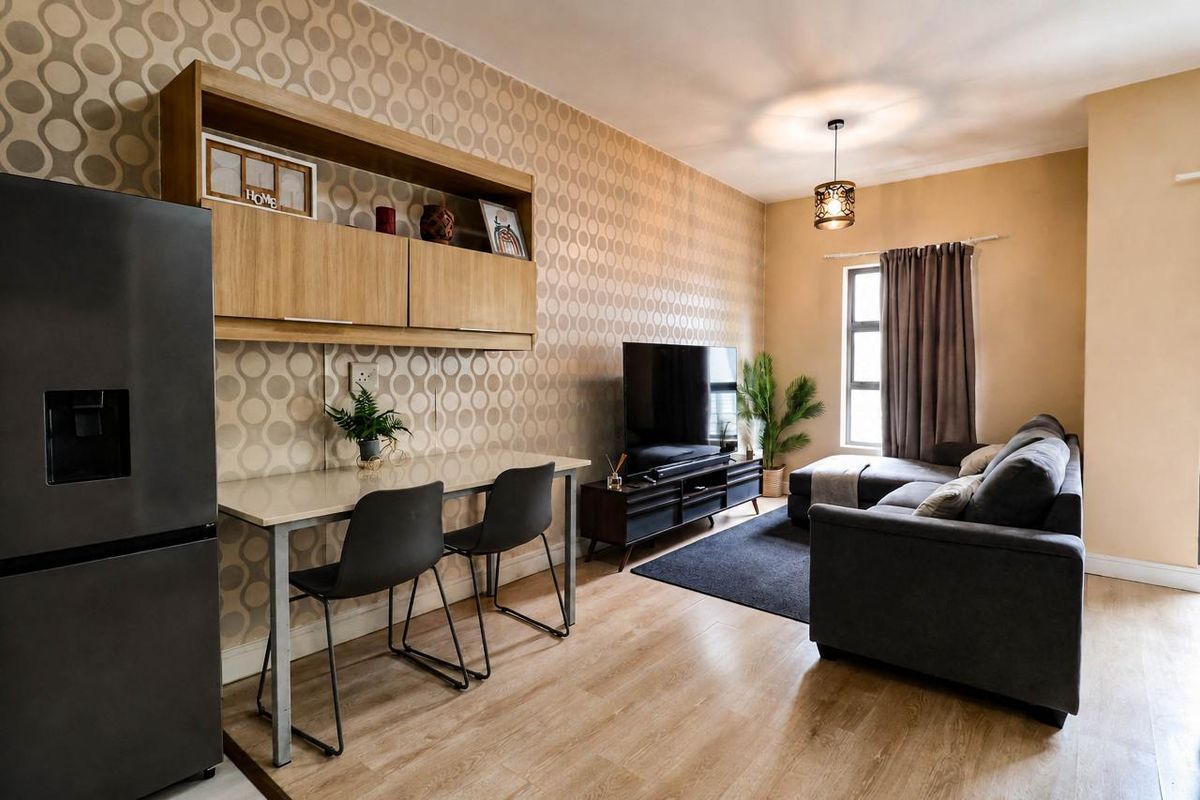 A well-maintained living room featuring laminate flooring, built-in wall cabinetry, and a modern pendant light fixture, creating a functional and comfortable living space.