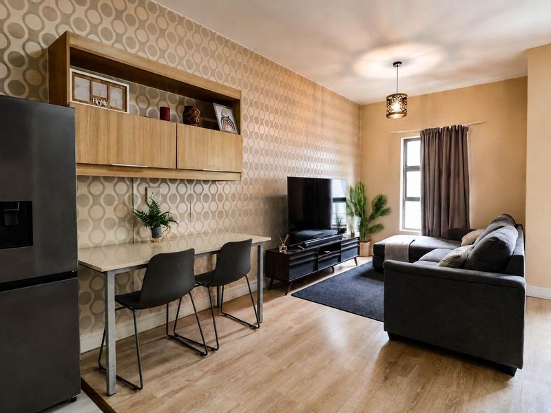 A well-maintained living room featuring laminate flooring, built-in wall cabinetry, and a modern pendant light fixture, creating a functional and comfortable living space.