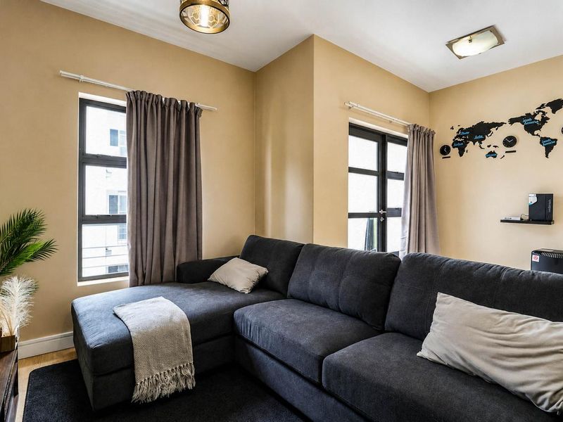 A well-lit living room featuring neutral wall tones, modern aluminium window frames, and contemporary ceiling lighting fixtures.